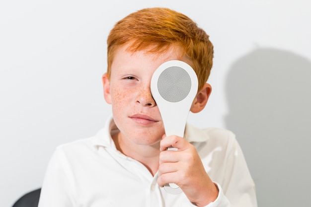 Portrait of boy covered eye with occluder in optics clinic