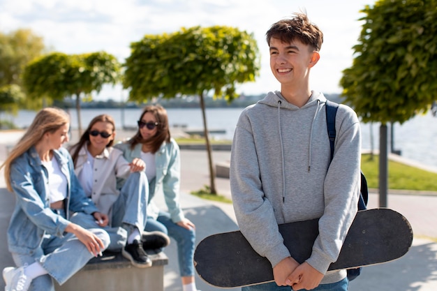 Portrait of boy holding a skateboard next to his friends