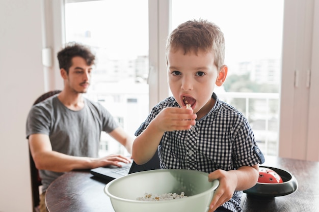 Portrait of a boy sitting on table eating popcorn