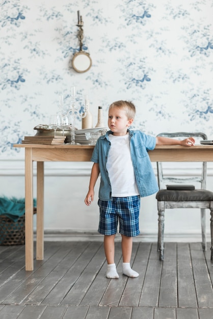 Free photo portrait of a boy standing near the table in the living room