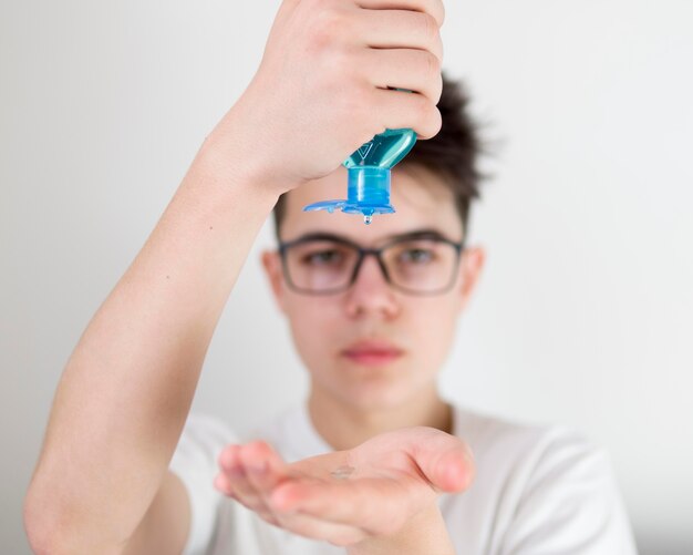 Portrait boy using hand sanitizer