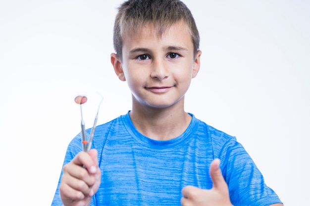 Portrait of a boy with dental instruments gesturing thumbs up