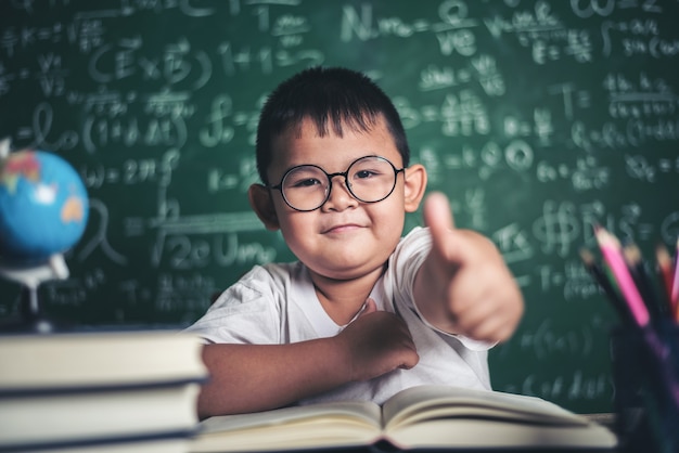 Free photo portrait of a boy with hands thumbs up in the classroom.