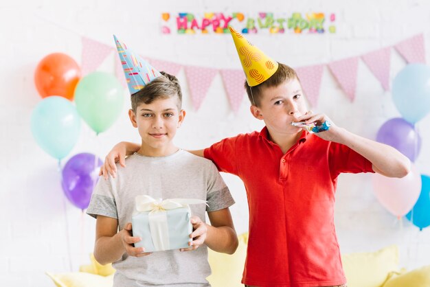 Portrait of boy with his friend holding birthday gift