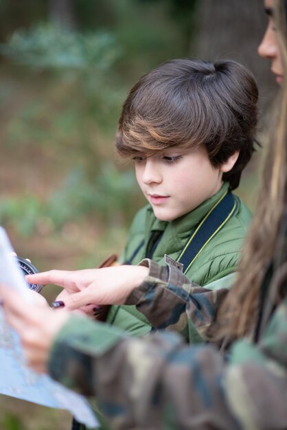 Portrait of boy and woman  looking at map. Dark-haired schoolboy and mother in coats studying map. Nature, leisure concept