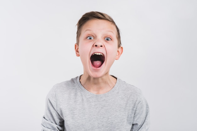 Portrait of a boy yelling loudly against grey background