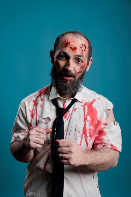 Portrait of brain eating zombie in studio having bloody wounds and dirty scars, acting dangerous and deadly. Eerie apocalyptic monster looking evil and aggressive, crazy thriller devil.
