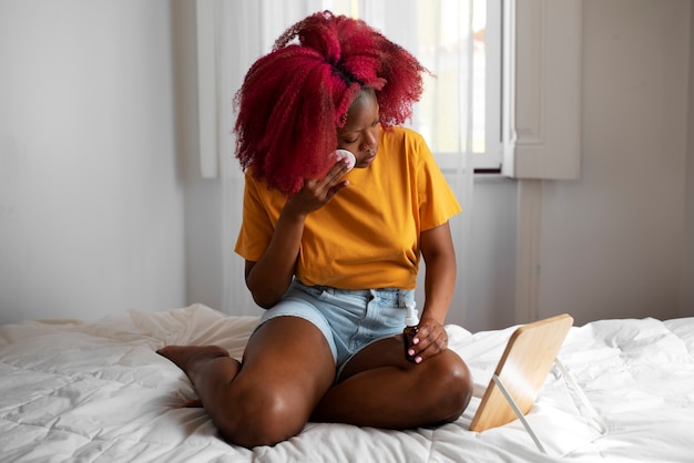 Free photo portrait of braless woman using mirror and make-up at home