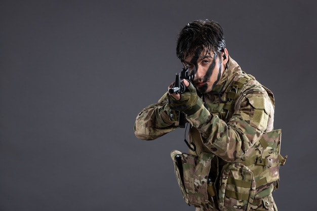Портрет храброго солдата в камуфляже с пулеметом на темной стене