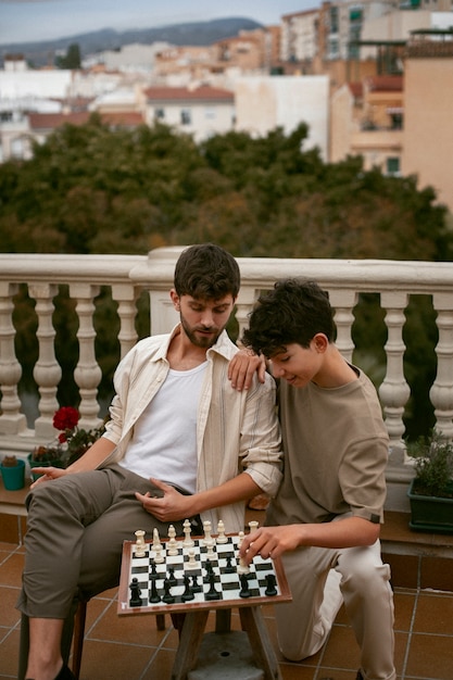 Foto gratuita ritratto di fratelli che giocano a scacchi insieme all'aperto
