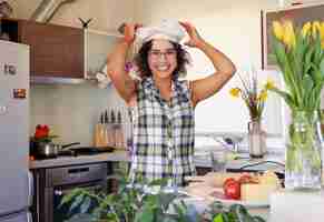 Foto gratuita ritratto di donna attraente bruna con capelli ricci in una cucina domestica con molti fiori.