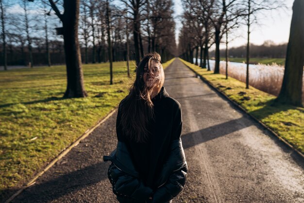 Ritratto di una ragazza bruna che si diverte in un parco sotto i raggi del sole splendente.