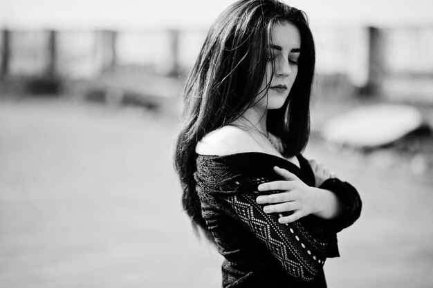 Portrait brunette girl with red lips wearing a black dress posed on the roof Street fashion model