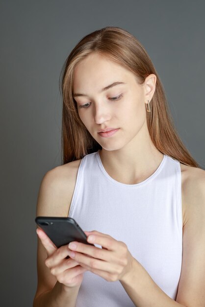 Portrait of brunette woman 20s using cell phone while standing isolated over yellow background