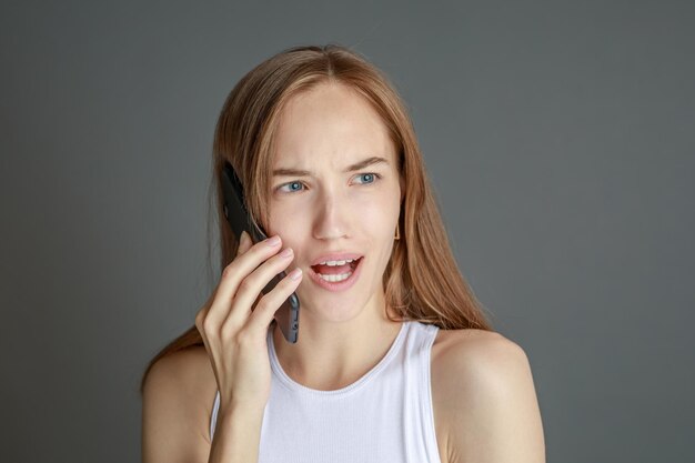 Portrait of brunette woman 20s using cell phone while standing isolated over yellow background