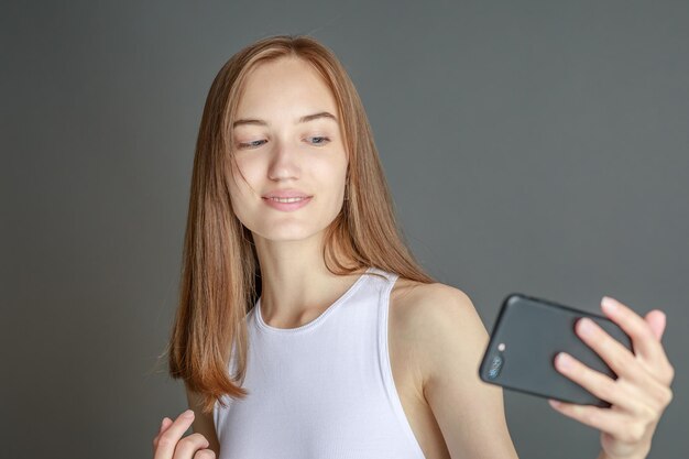 Портрет 20-летней брюнетки, использующей мобильный телефон, стоя изолированной на желтом фоне