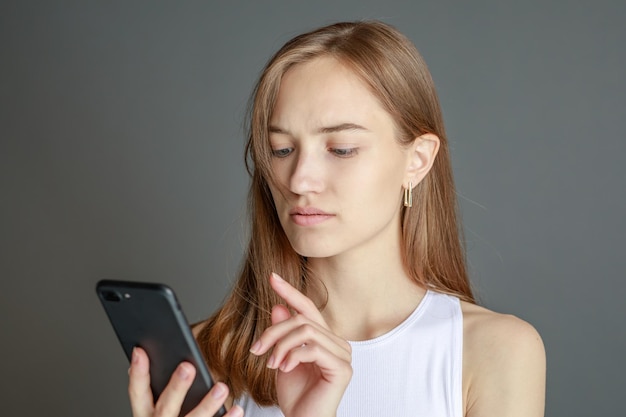 Portrait of brunette woman 20s using cell phone while standing isolated over yellow background