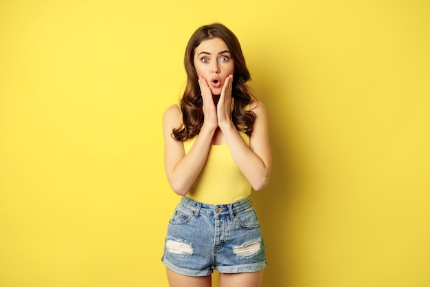 Portrait of brunette woman reacting surprised to advertsement gasping and saying wow wearing summer ...
