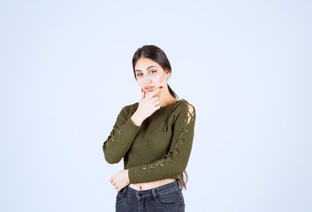 Portrait of brunette woman standing and holding her chin.