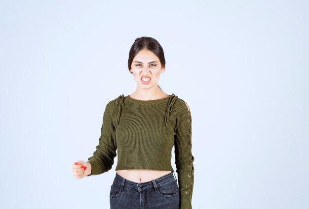 Portrait of brunette woman standing and showing angry face on white background.