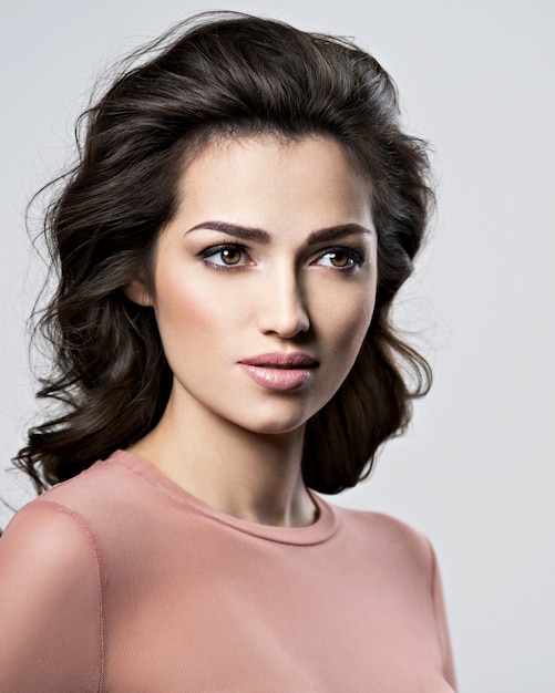 Portrait of brunette woman with beautiful long brown hair.  Pretty young adult girl posing at studio. Closeup attractive female face.