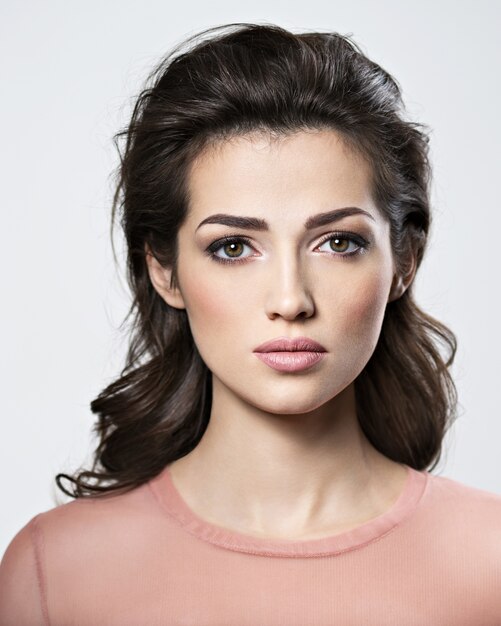 Portrait of brunette woman with beautiful long brown hair.  Pretty young adult girl posing at studio. Closeup attractive female face.