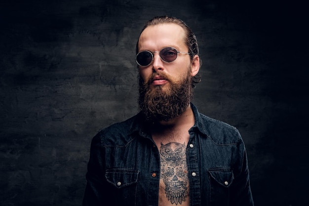 Portrait of brutal bearded man in sunglasses at dark photo studio.