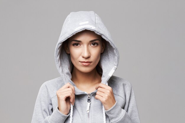 Portrait of brutal sportive woman in hood and sportswear on white.