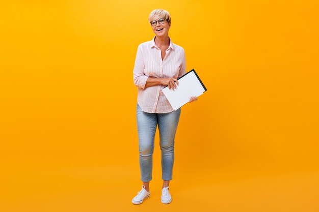 Portrait of business lady in jeans and shirt on orange background