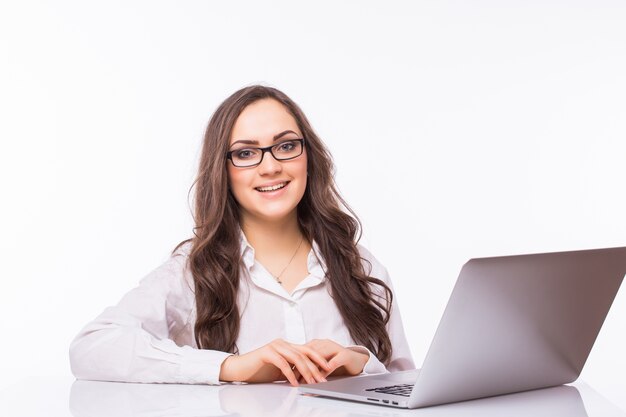 Portrait of Business woman sitting on her desk working with laptop isolated over white wall.