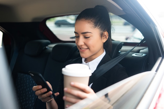 Free photo portrait of business woman using her mobile phone on way to work in a car. business concept.