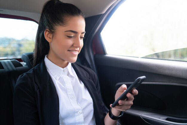 차에서 일하러 가는 길에 휴대전화를 사용하는 비즈니스 여성의 초상화