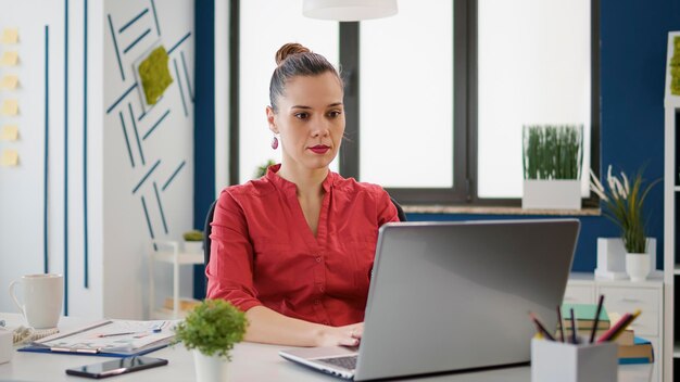 Free photo portrait of business woman working with sales charts on laptop, using financial statistics to plan executive strategy. project manager analyzing data research on graphs for startup growth.