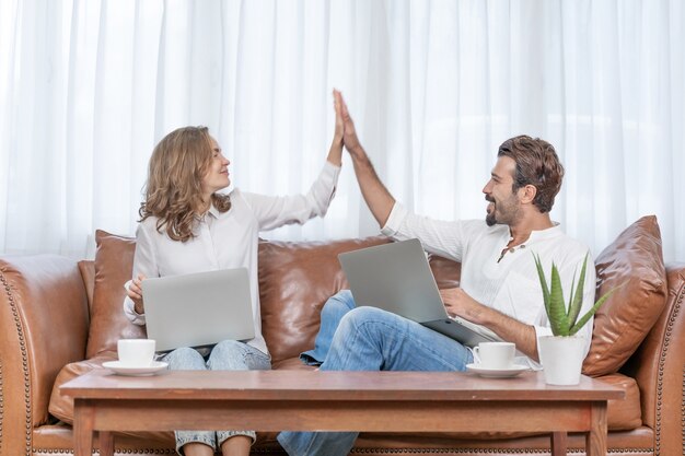 Portrait  businessman and  business woman give hi5 using the computer laptop at home office