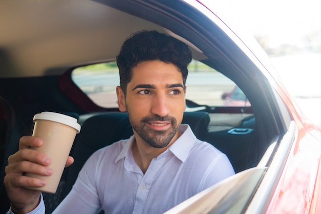 Ritratto di uomo d'affari che beve caffè mentre va al lavoro in macchina