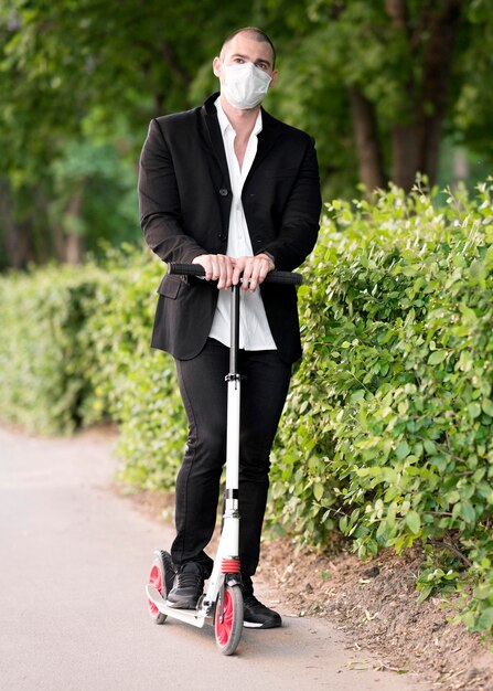 Portrait businessman riding scooter with medical mask