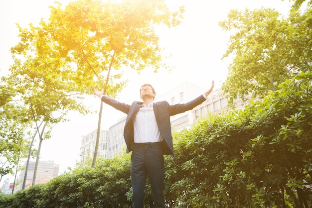 Portrait of a businessman standing in front of building raising his arms