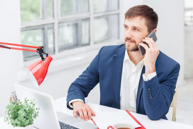 Portrait of businessman talking on phone in office