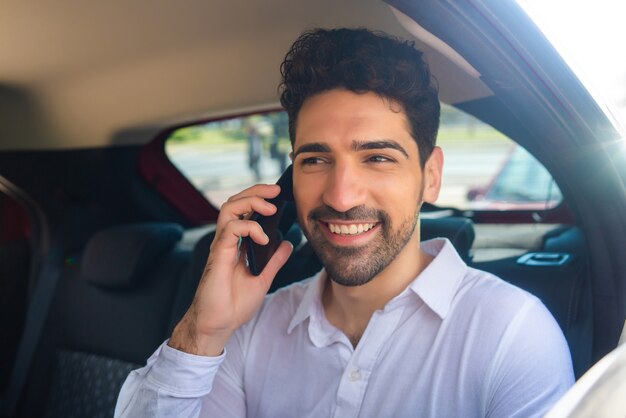 Portrait of businessman talking on phone on way to work in a car