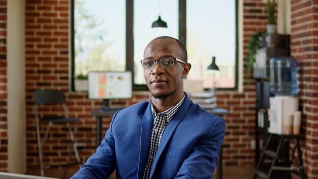 Portrait of businessman using laptop to browse internet in startup office, doing project research. Executive manager sending paperwork email, working on website browser application.