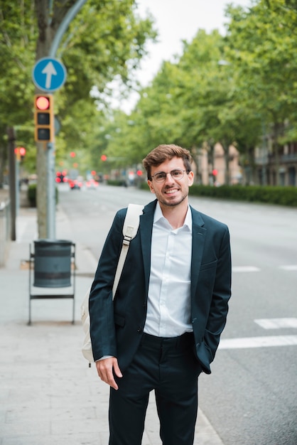 Free photo portrait of a businessman with hand in his pocket standing on city street