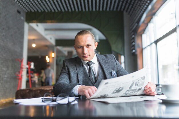 Портрет бизнесмена с газетой, сидящей в кафе