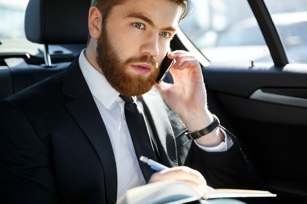 Portrait of a businessman with papers calling on smartphone