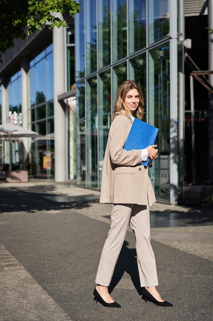 ベージュのスーツとハイヒールで女性実業家の肖像画は、wo に行く通りの企業の女性の上を歩いて