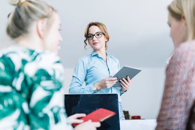 Portrait of businesswoman holding digital tablet talking with her colleagues