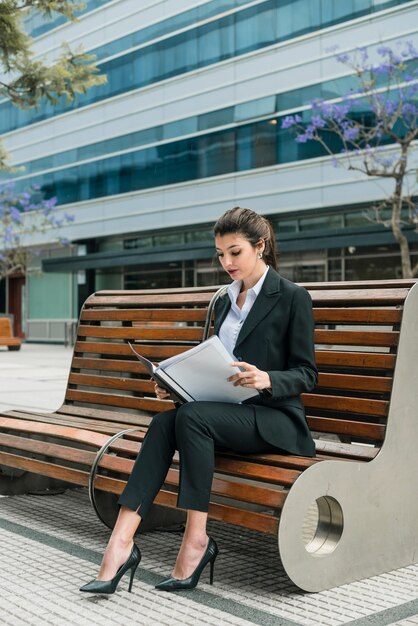 Portrait of a businesswoman sitting on bench reading folder