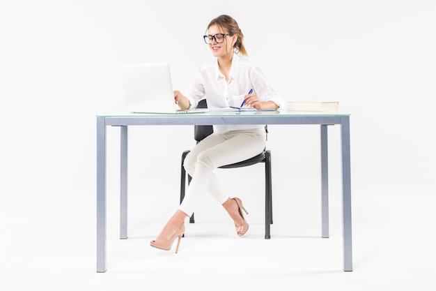 Portrait of a businesswoman sitting at a desk with a laptop isolated on white background