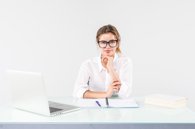 Портрет предпринимательницы, сидящей за столом с ноутбуком на белом фоне