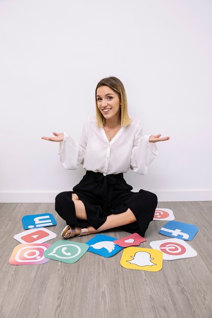 Portrait of businesswoman sitting with social media icons gesturing