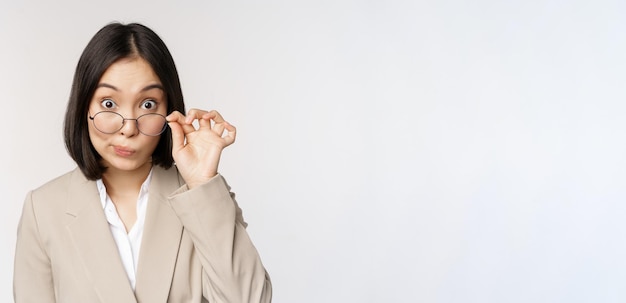 Portrait of businesswoman takeoff glasses and looking surprised at camera standing over white background